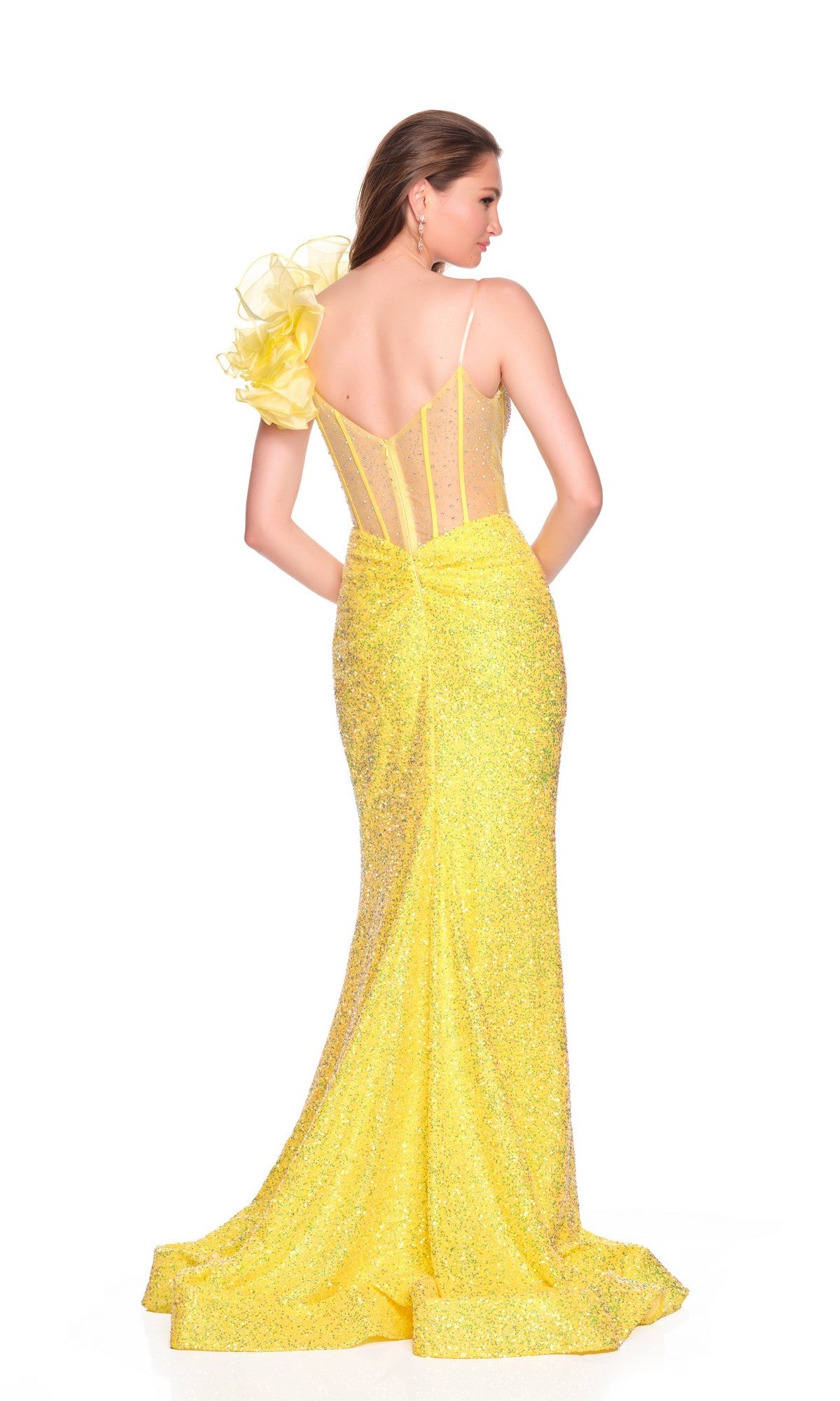 A woman wearing the Dave and Johnny 12475 long prom dress—a yellow, glittery, floor-length gown with a corset bodice, sheer back, and ruffled shoulders—stands against a white background.